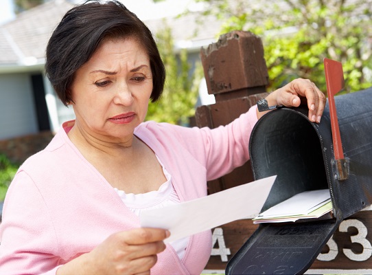 woman opening mail box scowling at check